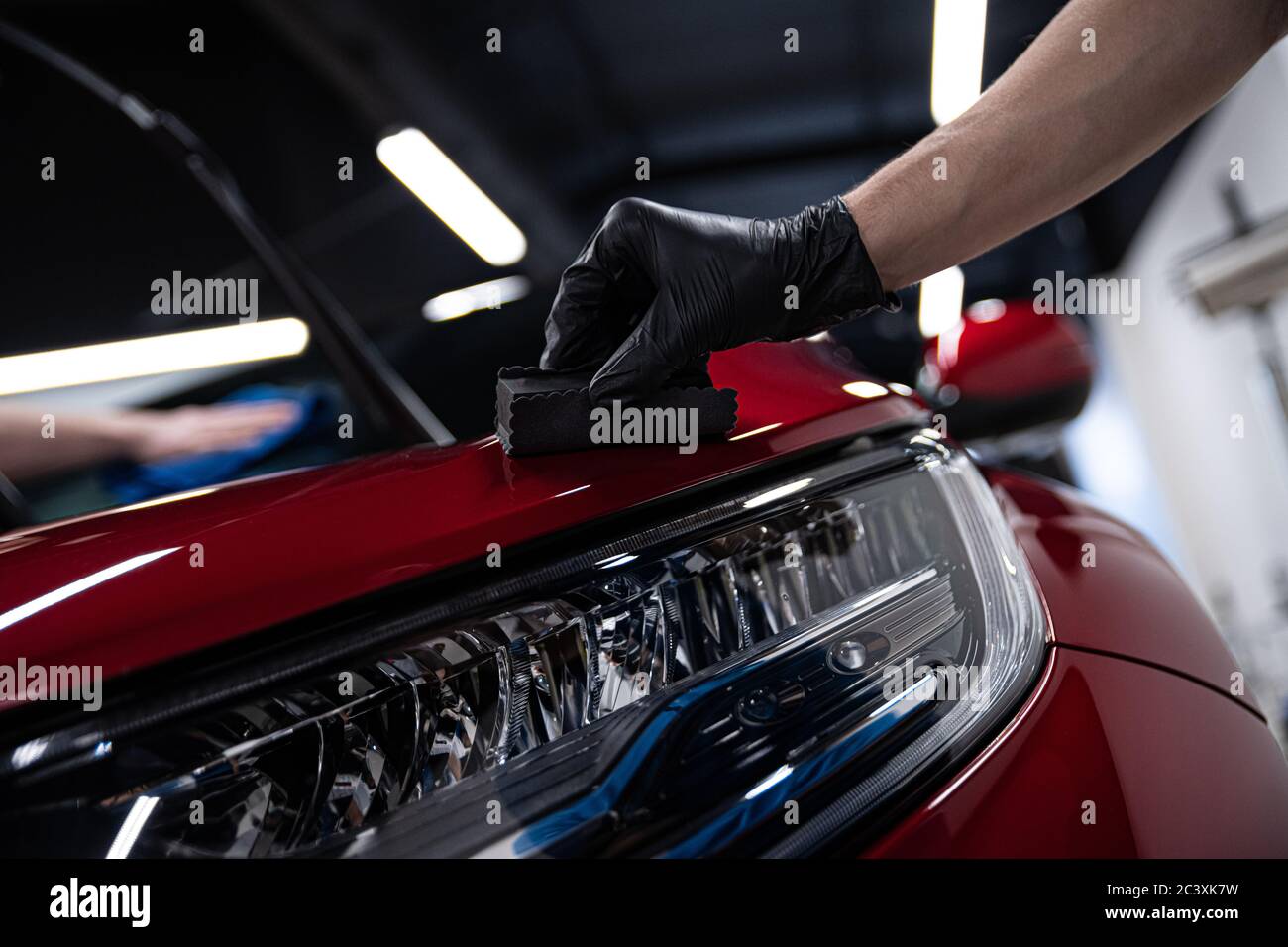 Man worker of car detailing studio applying ceramic coating on car
