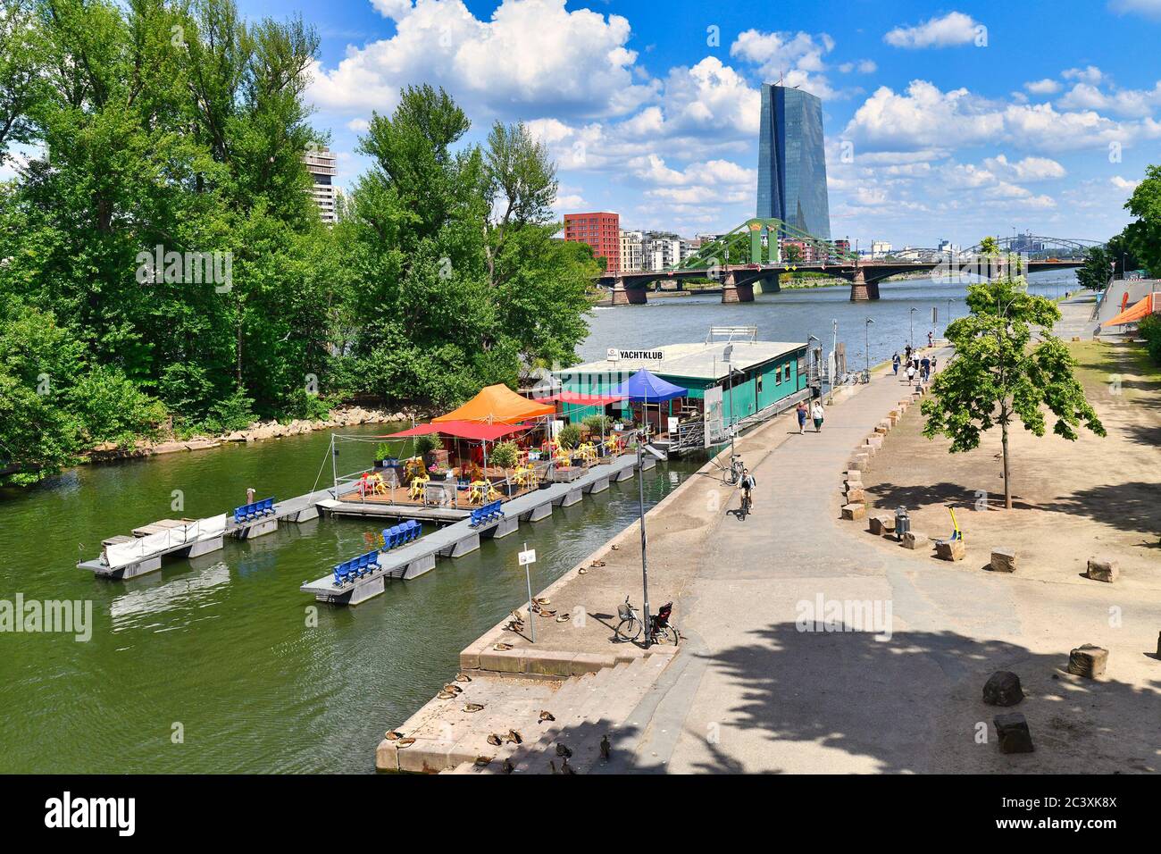 Frankfurt am Main, Germany - June 2020: Swimming restaurant on boat called 'Yachtclub' on Main river in Frankfurt on sunny day with skyscrapers Stock Photo