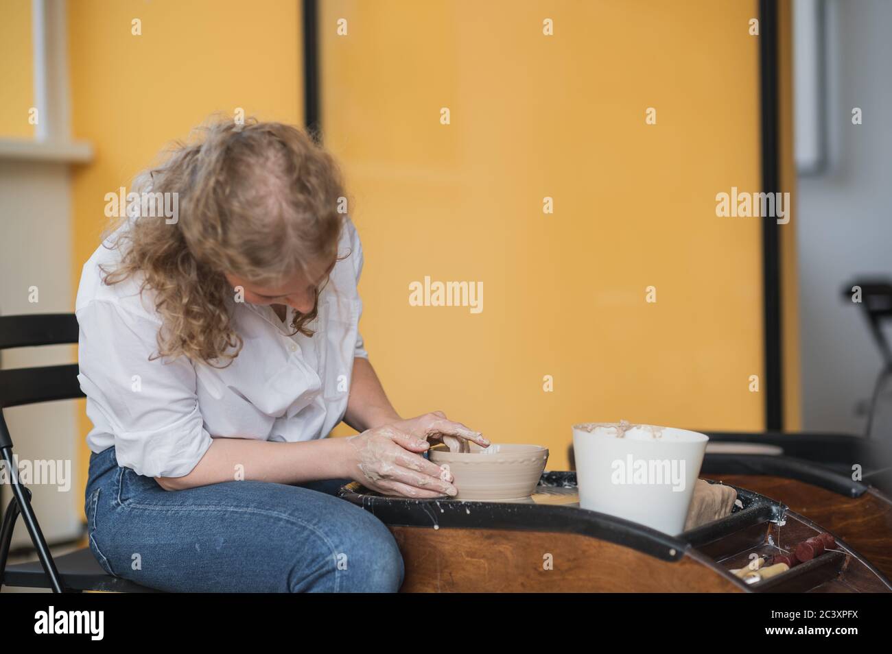 Potter makes the clay product with pottery modeling tools on the potter's wheel. Stock Photo