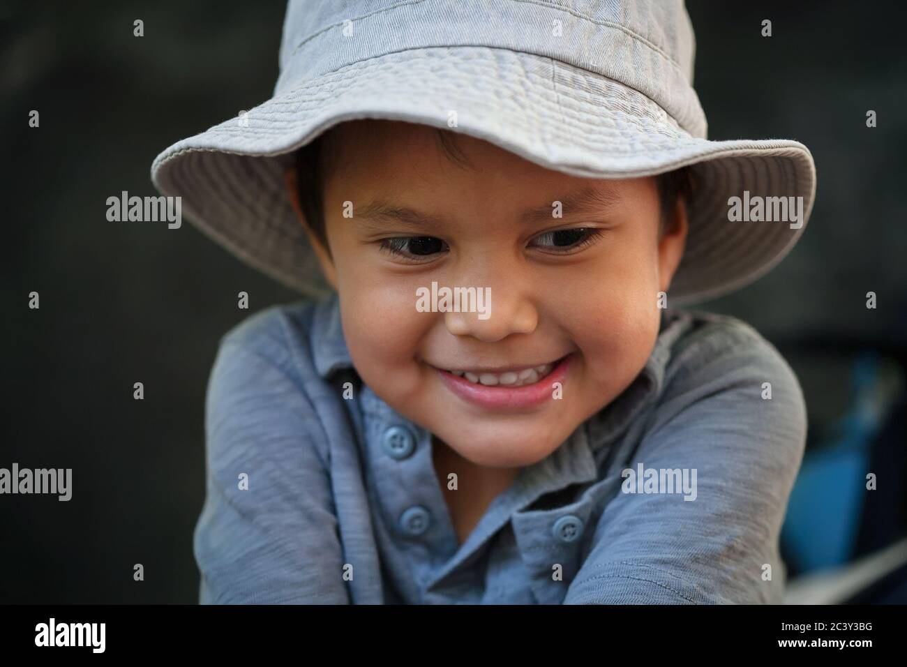 A little boy wearing a fisherman's hat and smiling, expressing happiness while fishing. Stock Photo