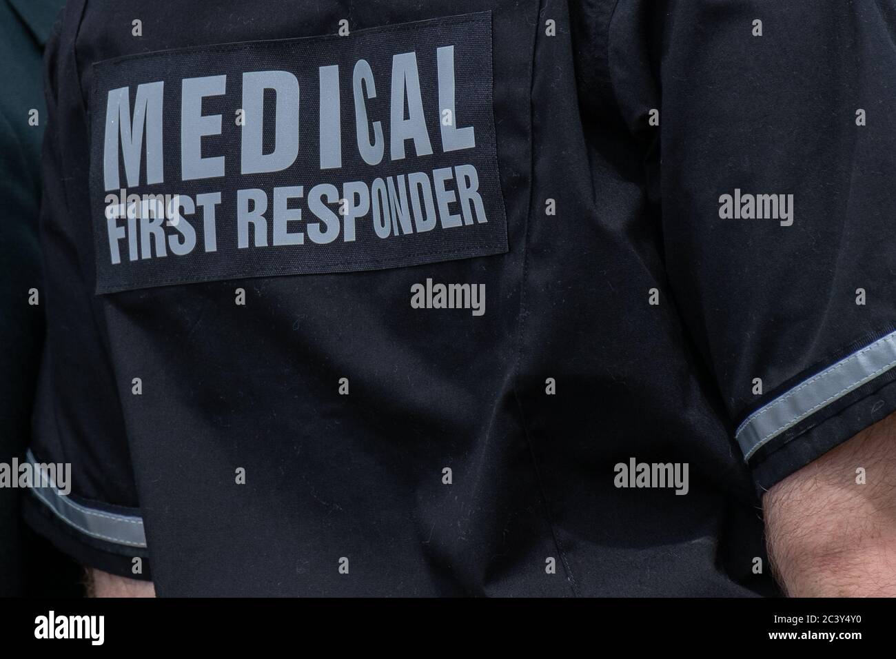 A medical officer wearing a medical first responder's uniform. The shirt is navy blue color with reflective grey letters and stripes. Stock Photo