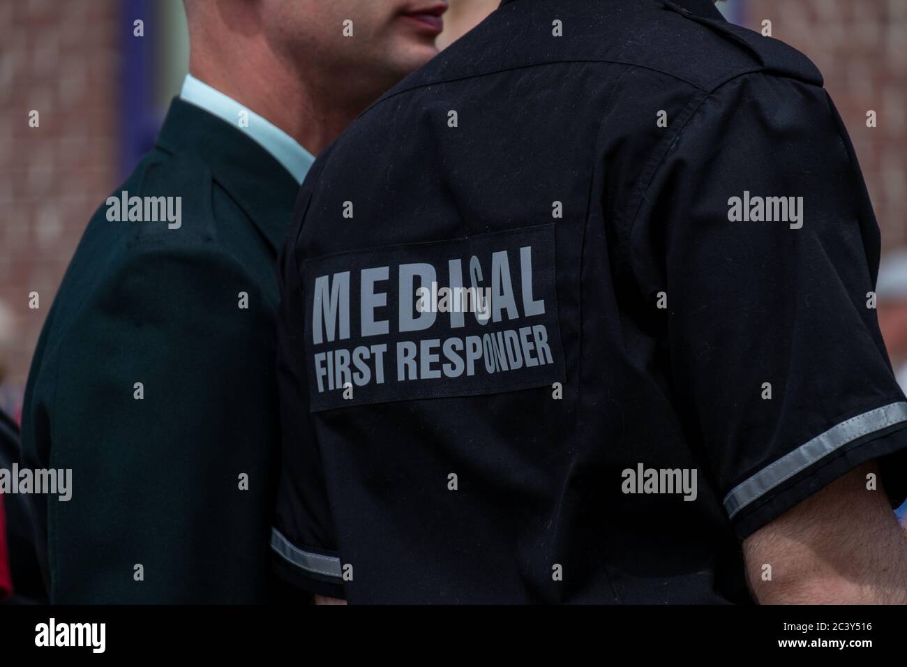 A medical officer wearing a medical first responder's uniform. The shirt is navy blue color with reflective grey letters and stripes. Stock Photo