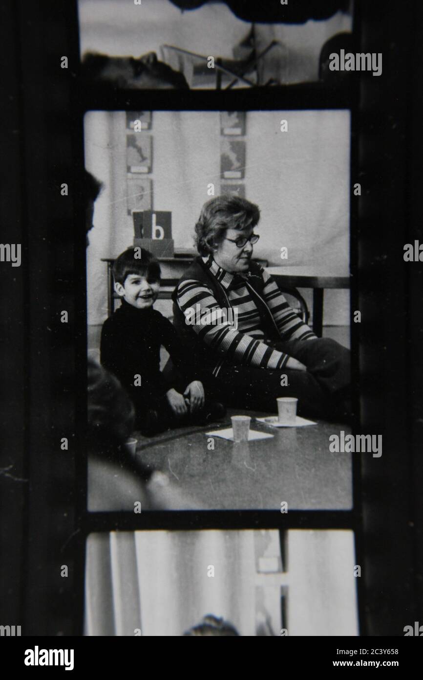 Fine 70s vintage contact print black and white extreme photography of a teacher and student sitting on the floor and following directions. Stock Photo