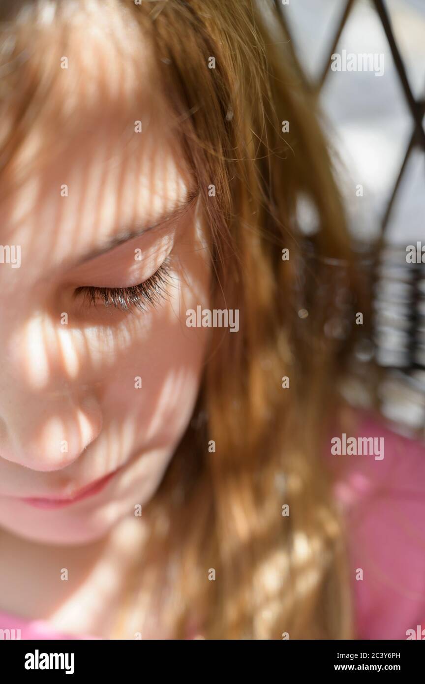 Close-up of girl (6-7) in dappled sunlight Stock Photo