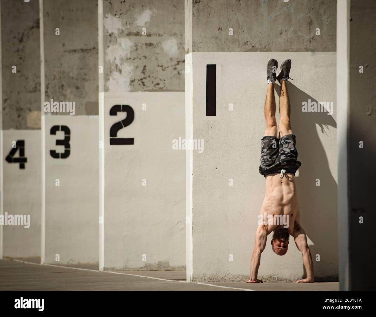 Man doing handstand next to wall Stock Photo