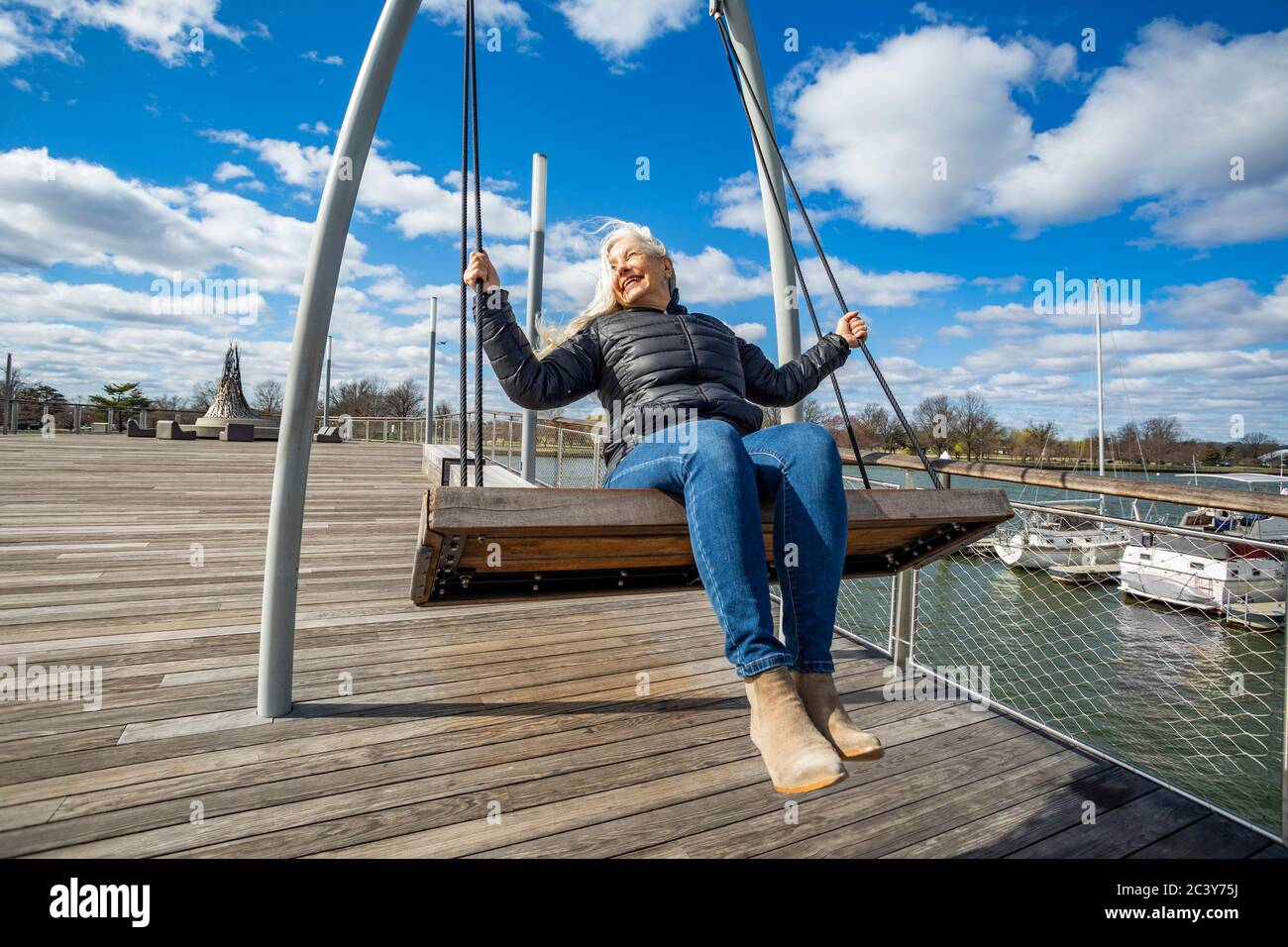 USA, Washington D.C., Senior woman on swing at Wharf District along Potomac River Stock Photo