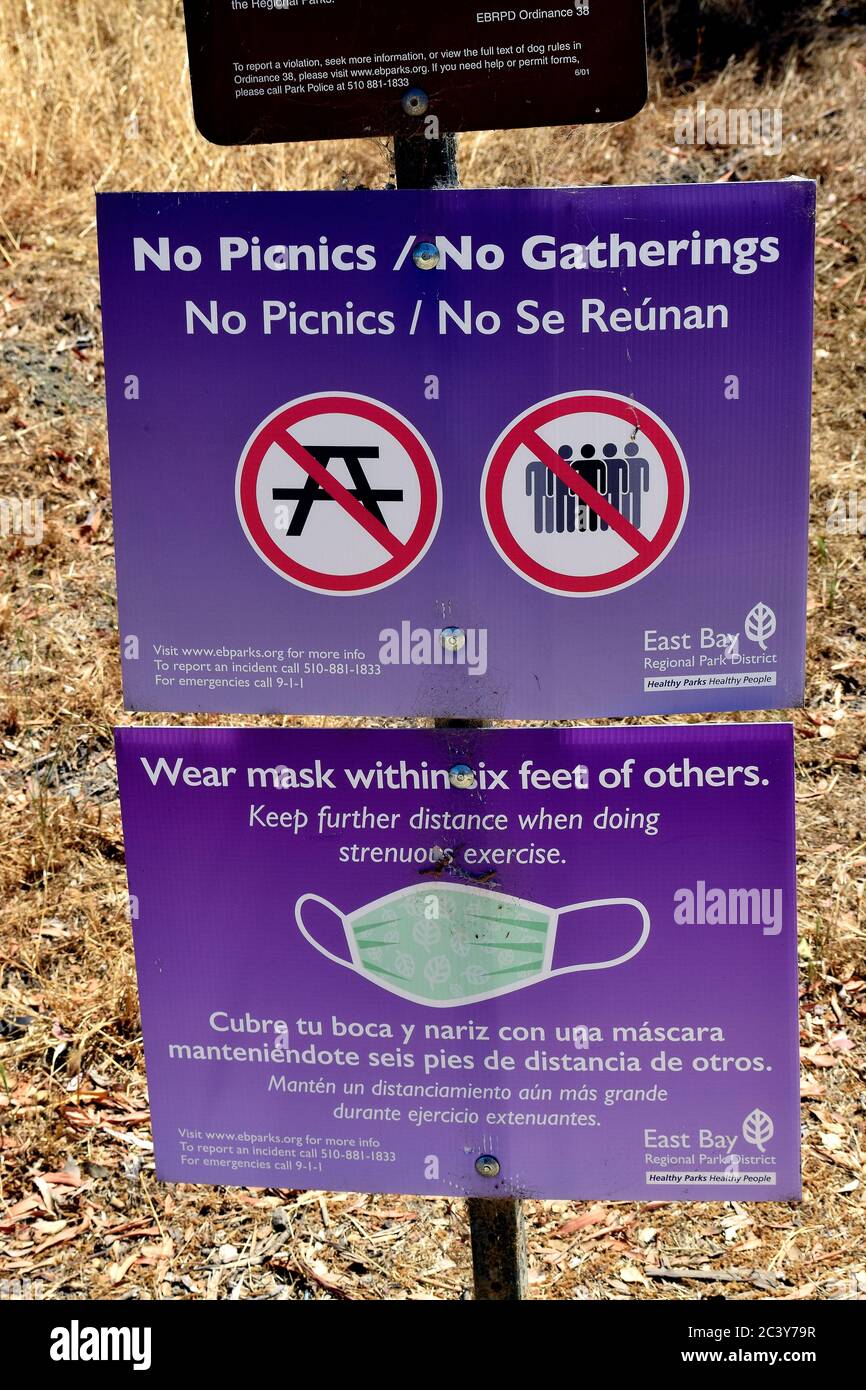 covid-19 virus pandemic sign on a picnic table prohibiting picnics and gatherings  and wear masks and social distancing, at the Alameda Creek Regional Trail Stables Staging Area, California Stock Photo