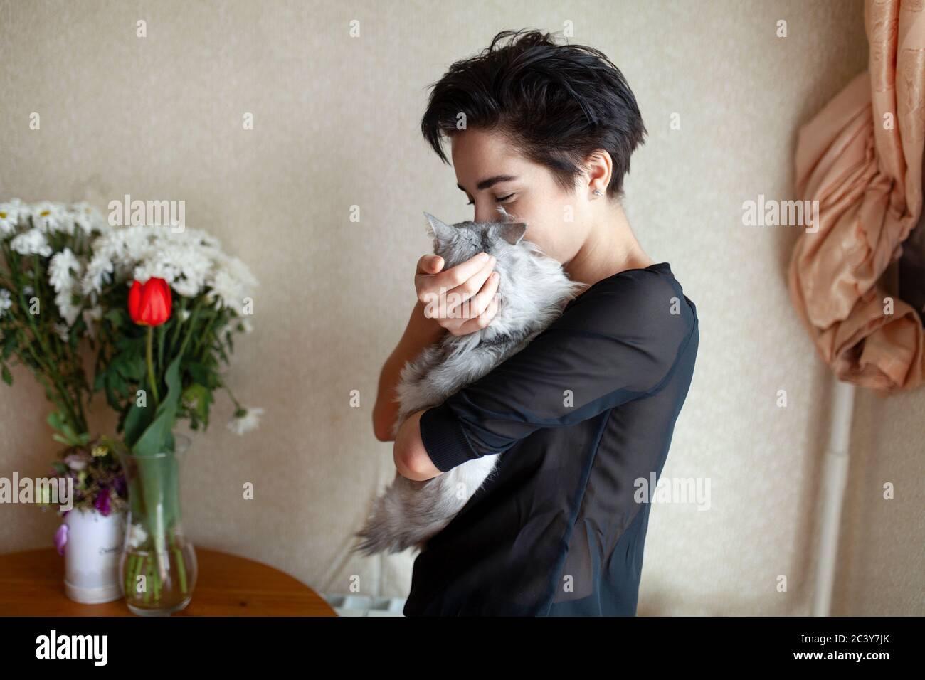 Woman cuddling cat at home Stock Photo