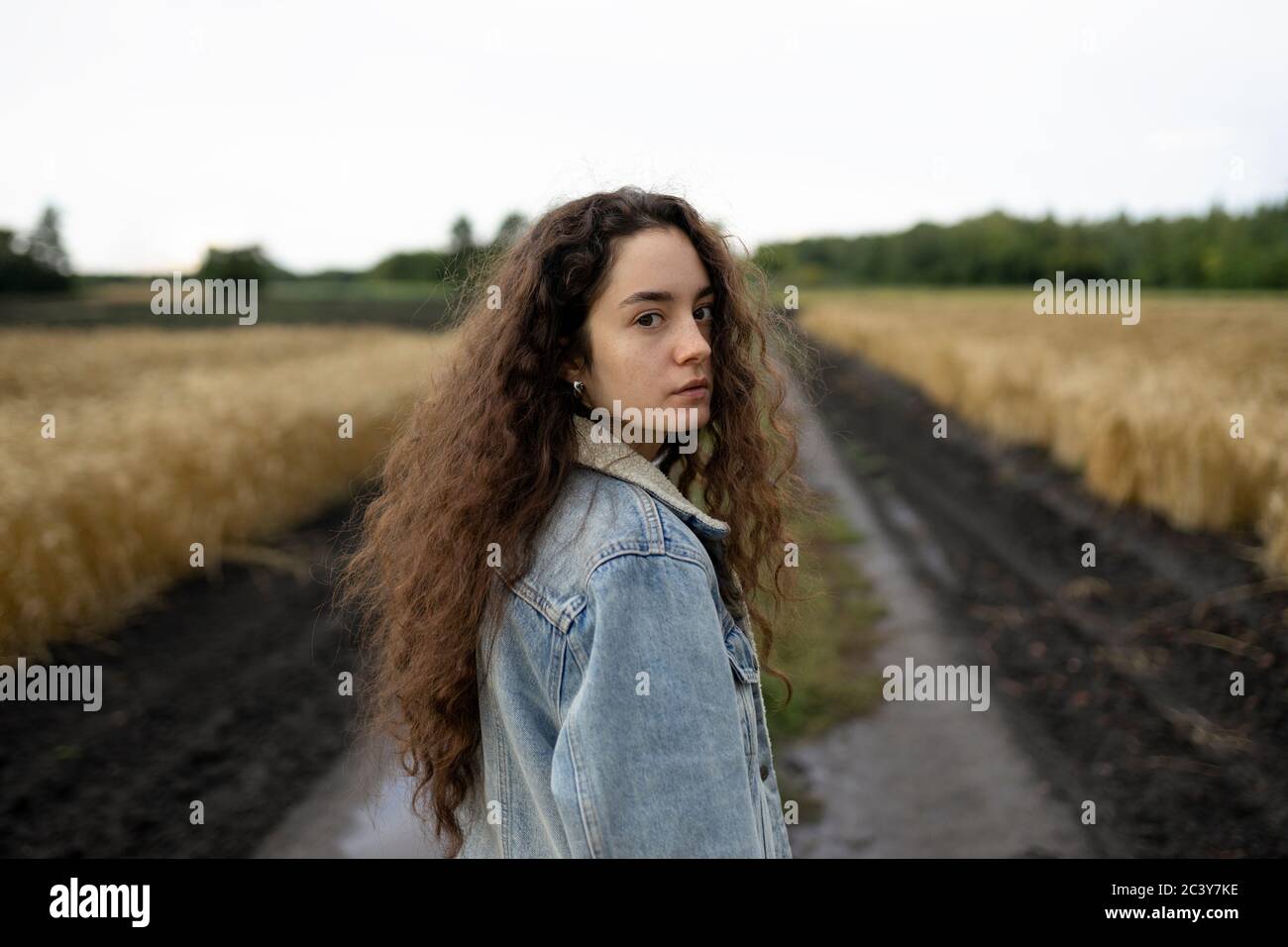 Russia, Omsk, Portrait of young woman with brown hair standing in field Stock Photo