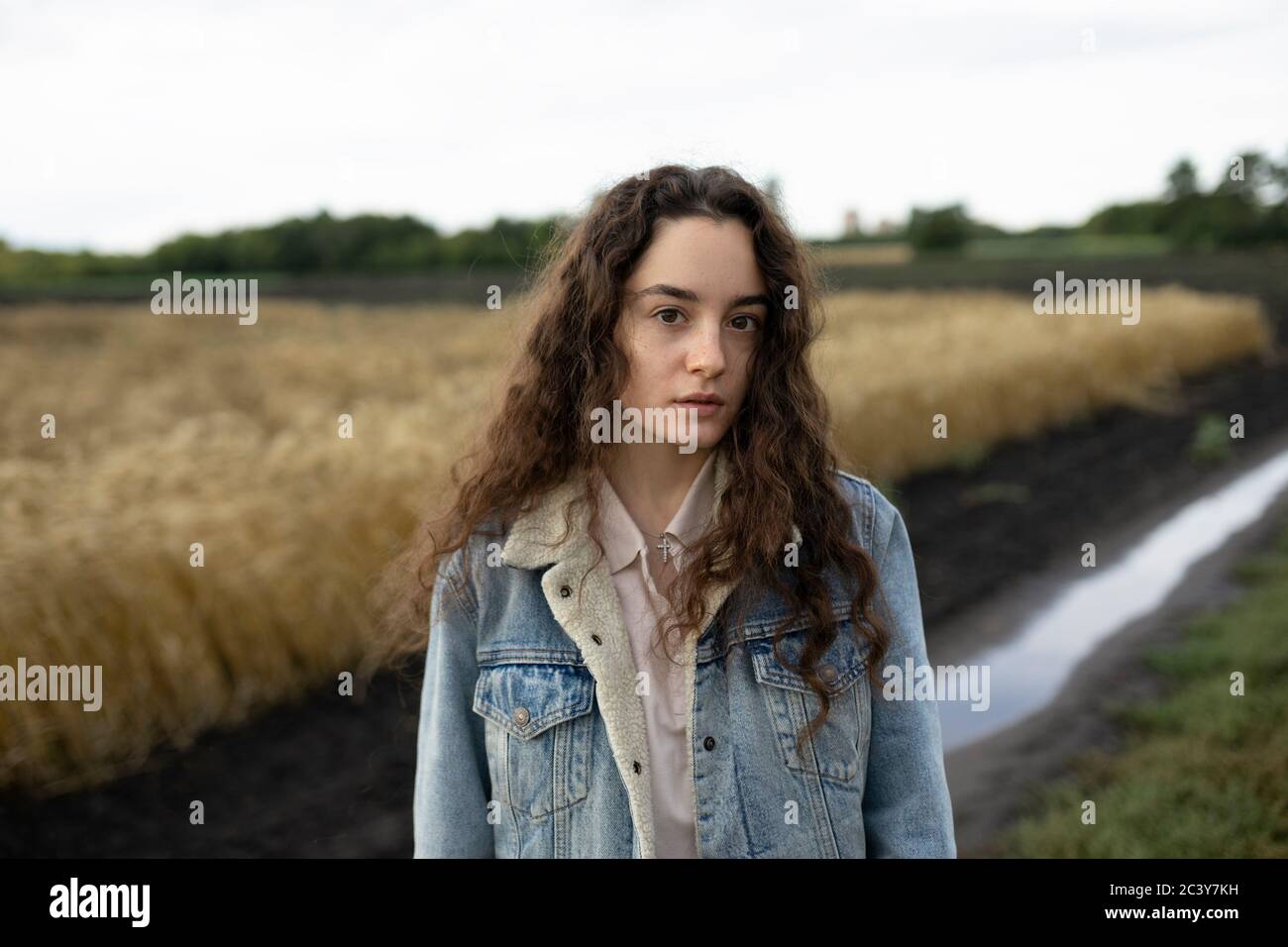 Russia, Omsk, Portrait of young woman with brown hair standing in field Stock Photo