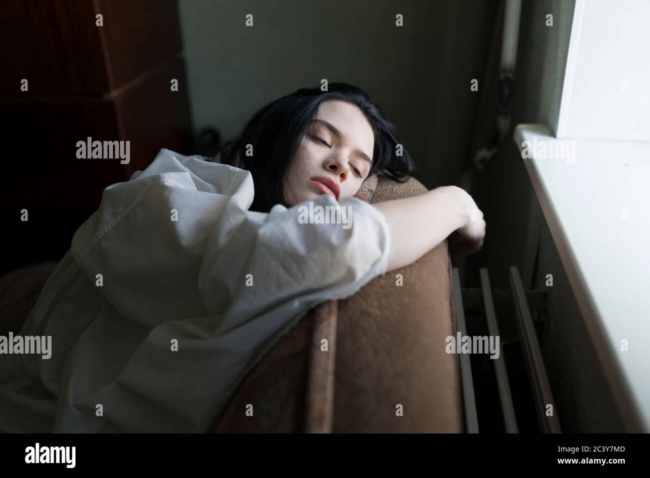 Young woman leaning by window Stock Photo - Alamy