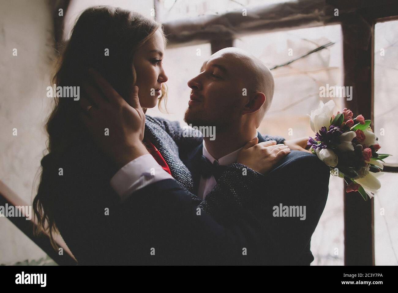 Newlywed couple embracing in window Stock Photo
