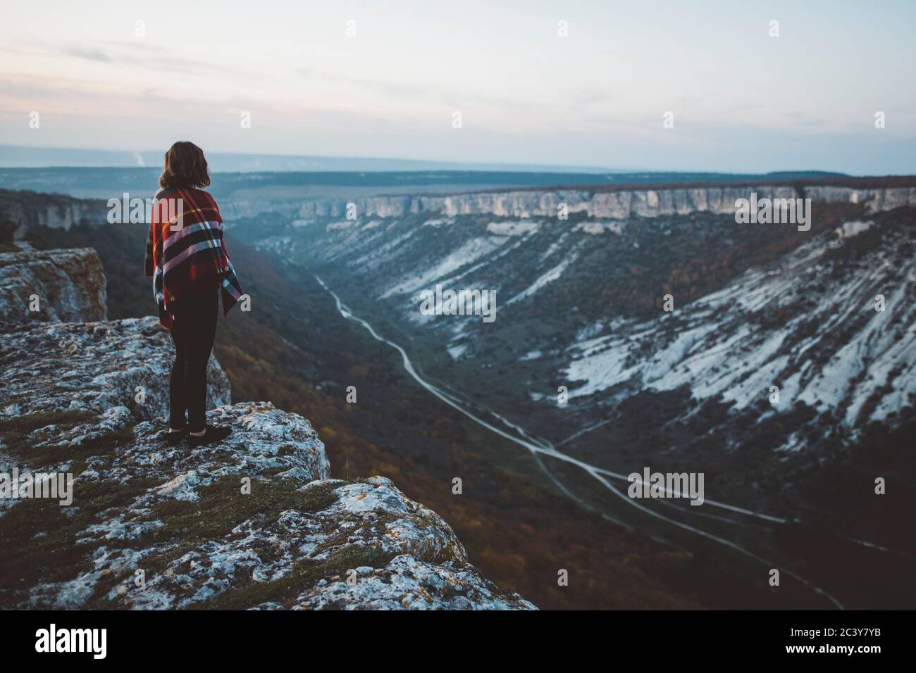 Ukraine, Crimea, Young woman covered with plaid looking at canyon Stock Photo