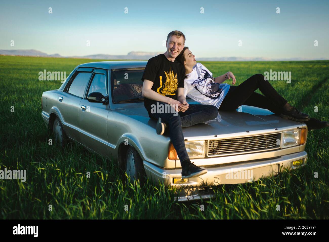 Ukraine, Crimea, Couple sitting on old fashioned car in rural scenery Stock Photo