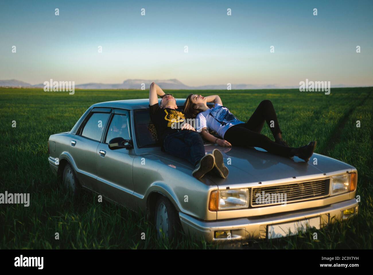 Ukraine, Crimea, Couple sitting on old fashioned car in rural scenery Stock Photo