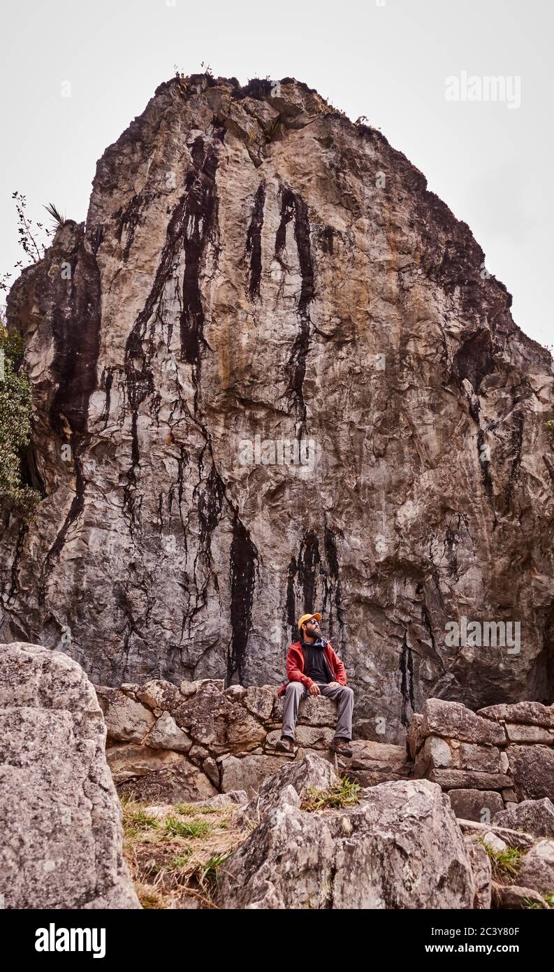 Peru, Machu Pichu, Man sitting in front of rock formation Stock Photo