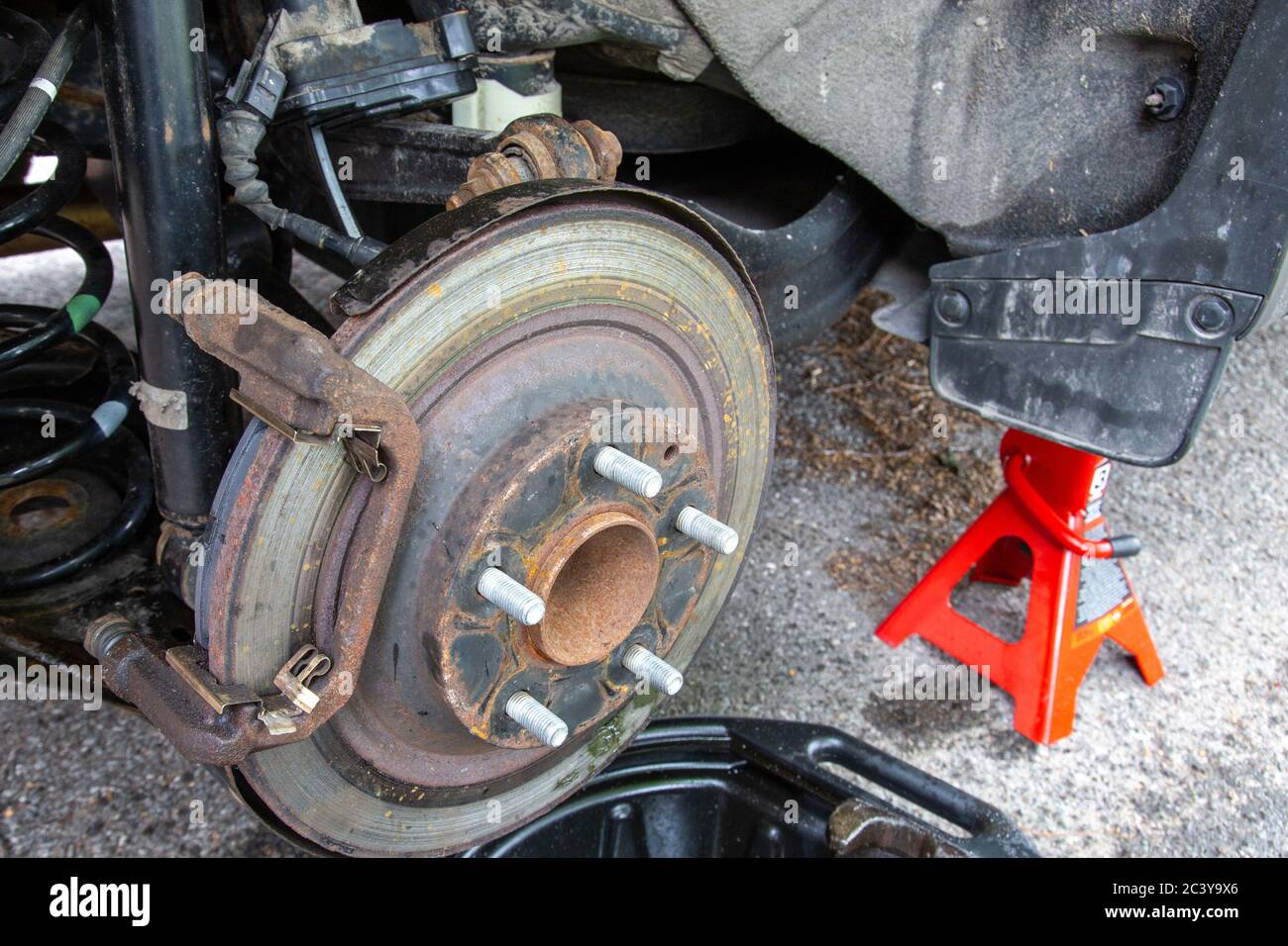 Brake work is being done on a car in a driveway. The vehicle sits on a