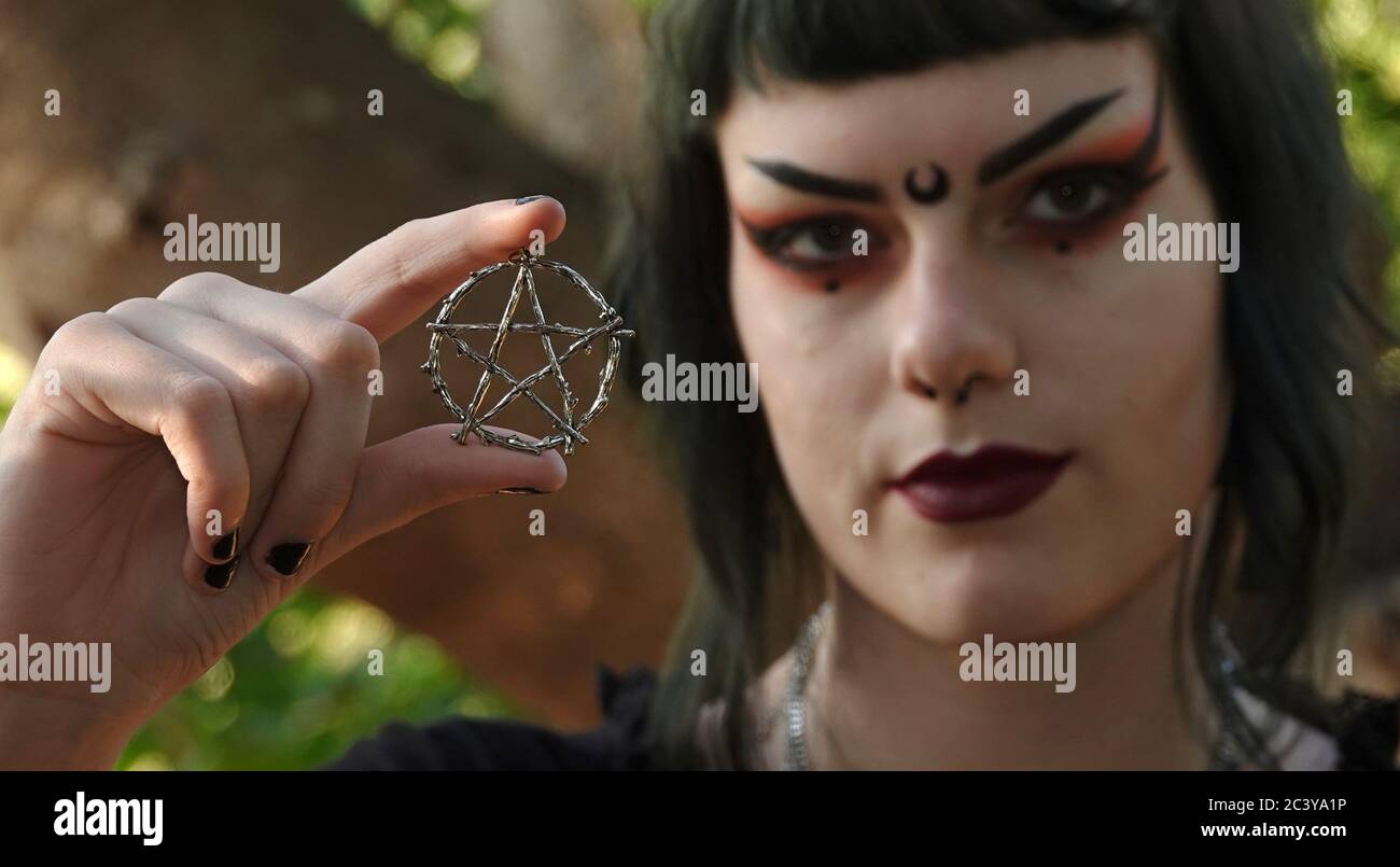 Close up of a silver pentacle held up by a teen Wiccan. Focus is on pentacle. Stock Photo