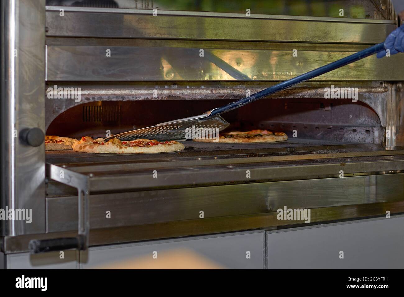 Putting pizza in oven at restaurant kitchen Stock Photo Alamy