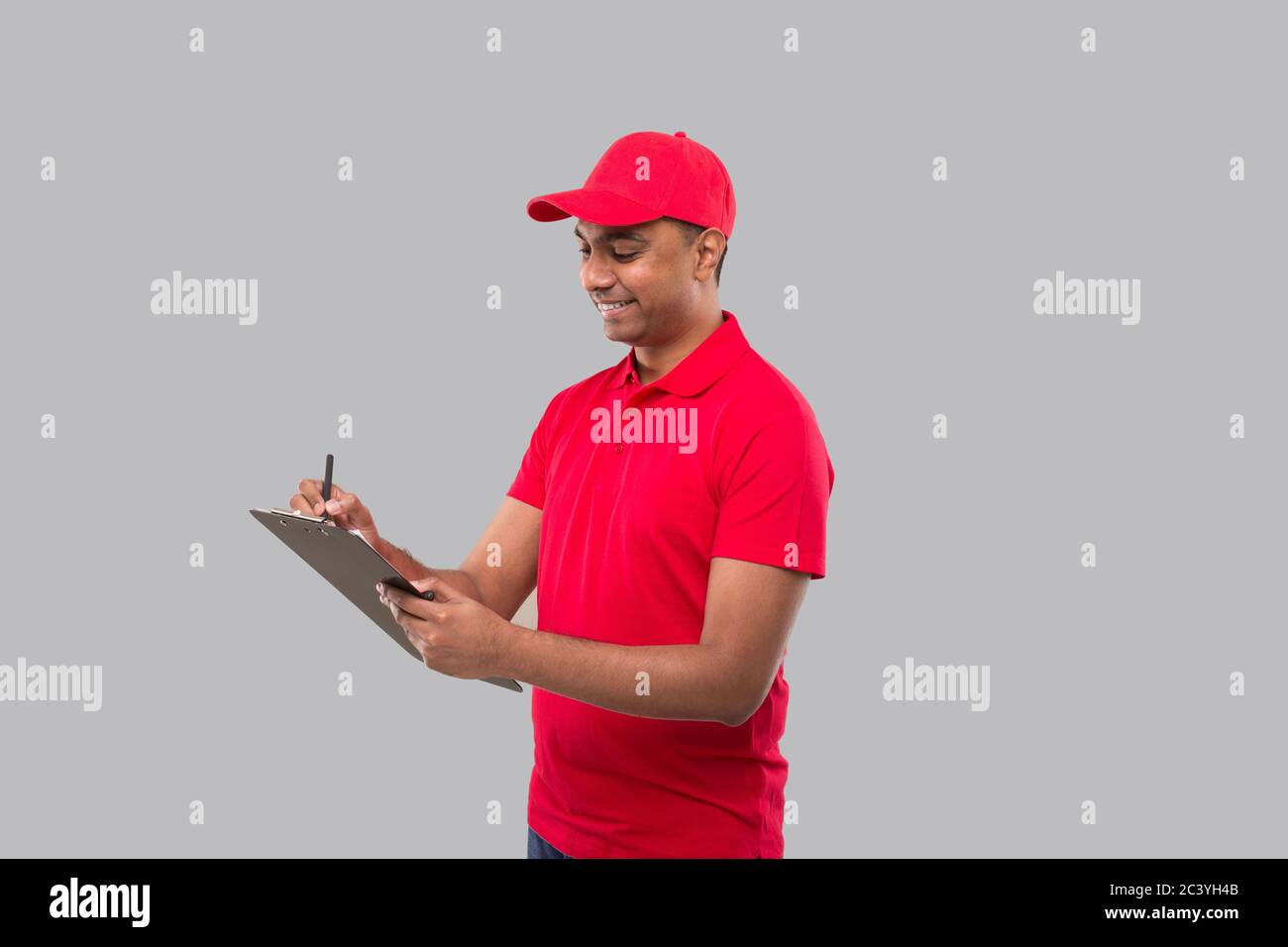 Delivery Man Writing in clipboard. Indian Delivery Boy Clipboard Stock Photo