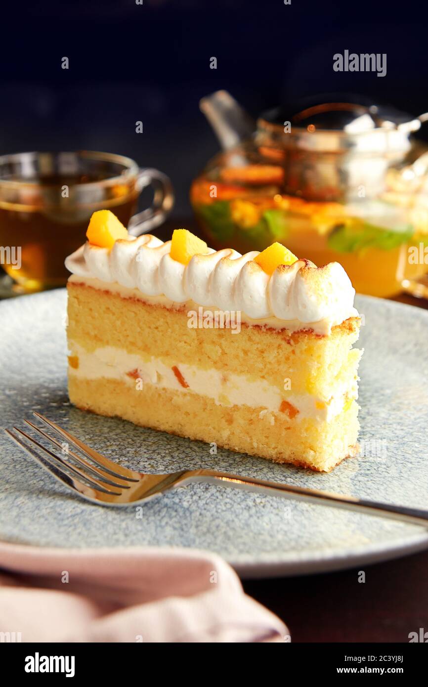 Piece of delicious cake with pineapple decorated with whipped cream, served  with pot and cup of citrus herbal tea on wooden table Stock Photo - Alamy