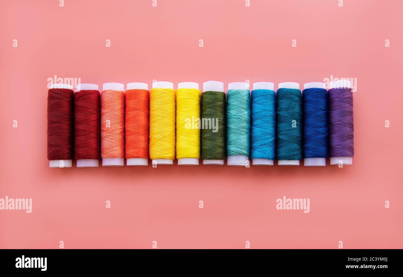 Spools of thread on the colors of the rainbow on a pink background ...