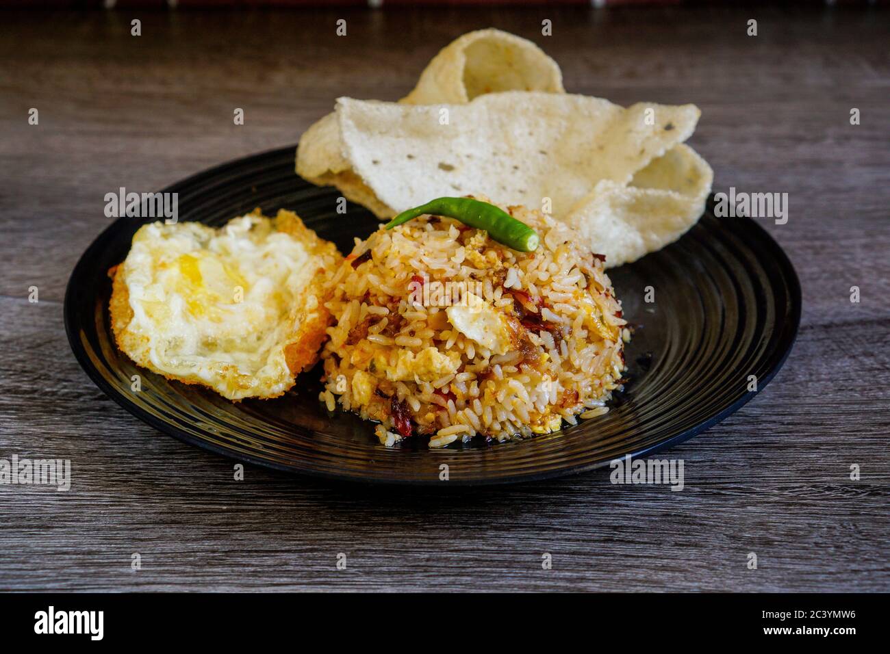 Spicy fried rice with dried chilli with fried egg and fish cracker. Stock Photo