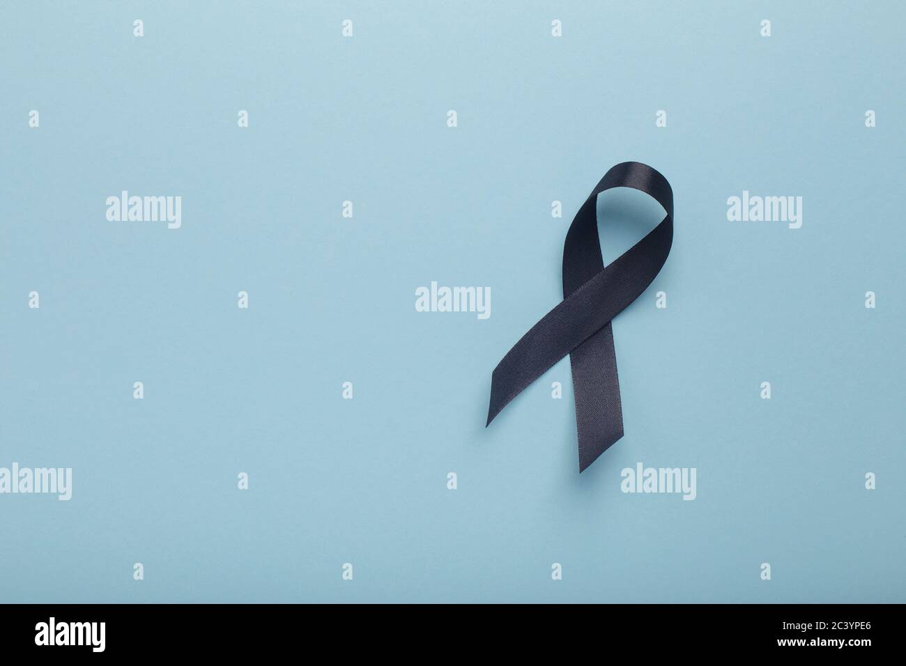 Black awareness ribbon Isolated on blue background Stock Photo