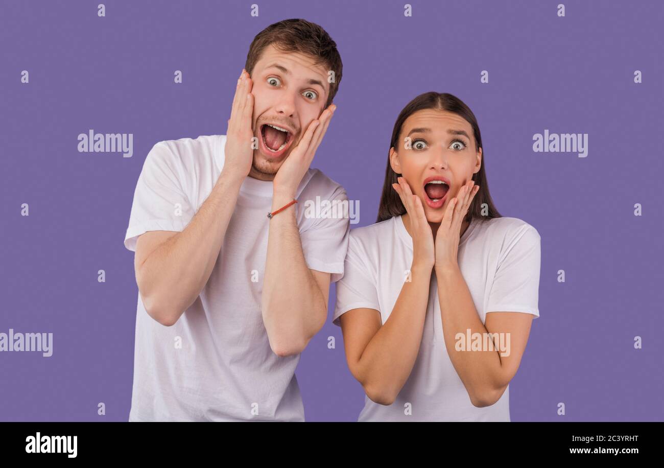 Excited young couple screaming happily at camera at studio Stock Photo