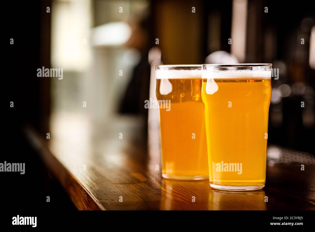 Evening meeting in pub. Two glasses with light beer on wooden bar counter Stock Photo