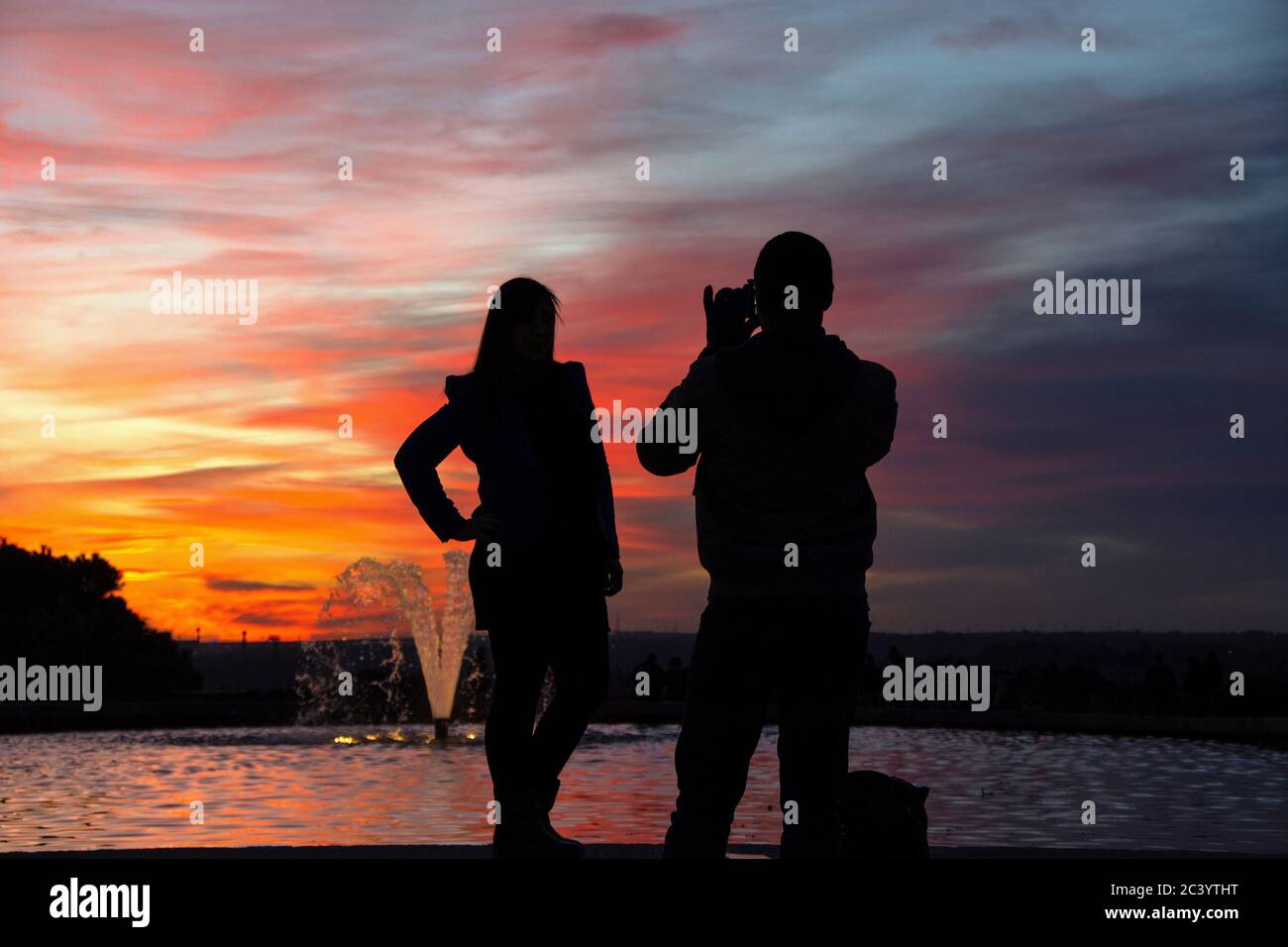 silhouette of a man holding a cellphone taking pictures outside during sunrise or sunset. Madrid. Stock Photo