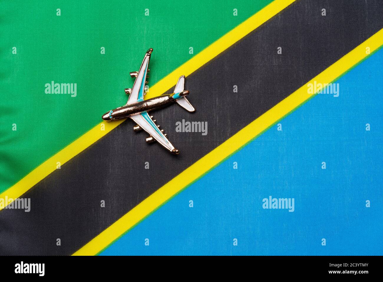 Plane over the flag of Tanzania the concept of travel and tourism. Toy plane on a flag in the background. Stock Photo