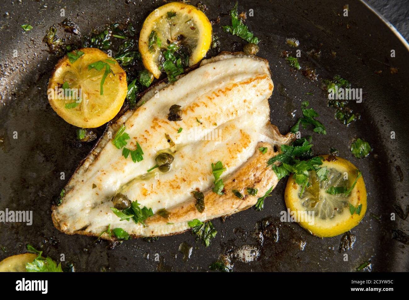 A home cooked fillet of lemon sole, Microstomus kitt, that has been pan fried in butter with lemon slices, capers and parsley. Dorset England UK GB Stock Photo