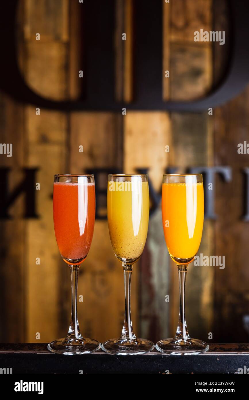 Three different sparkling fruity cocktails, red, yellow and orange, in flute glasses Stock Photo