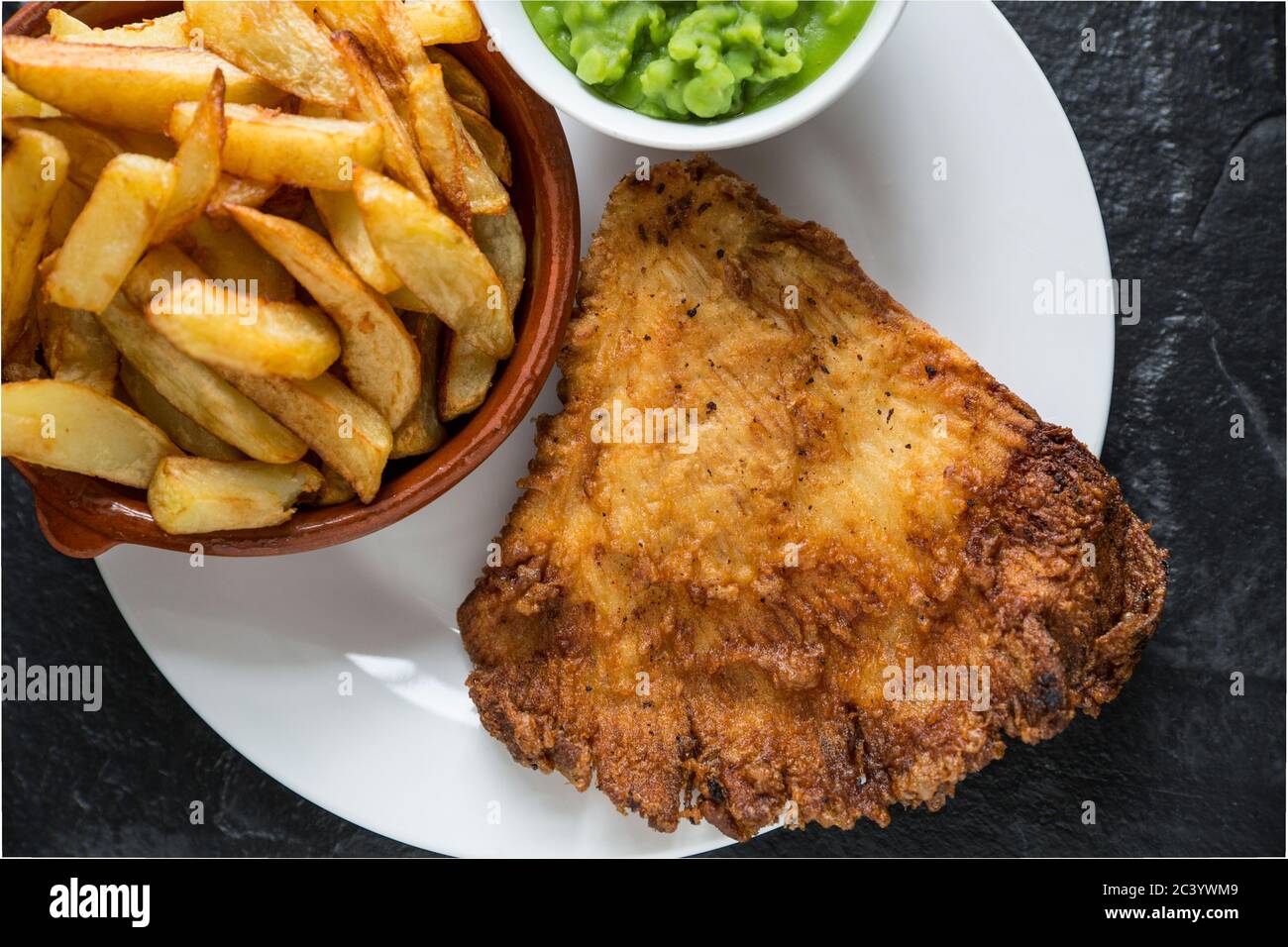 A home cooked portion of fish and chips with mushy peas. The fish is a deep fried, battered wing from a thornback ray, Raja clavata, and the chips are Stock Photo