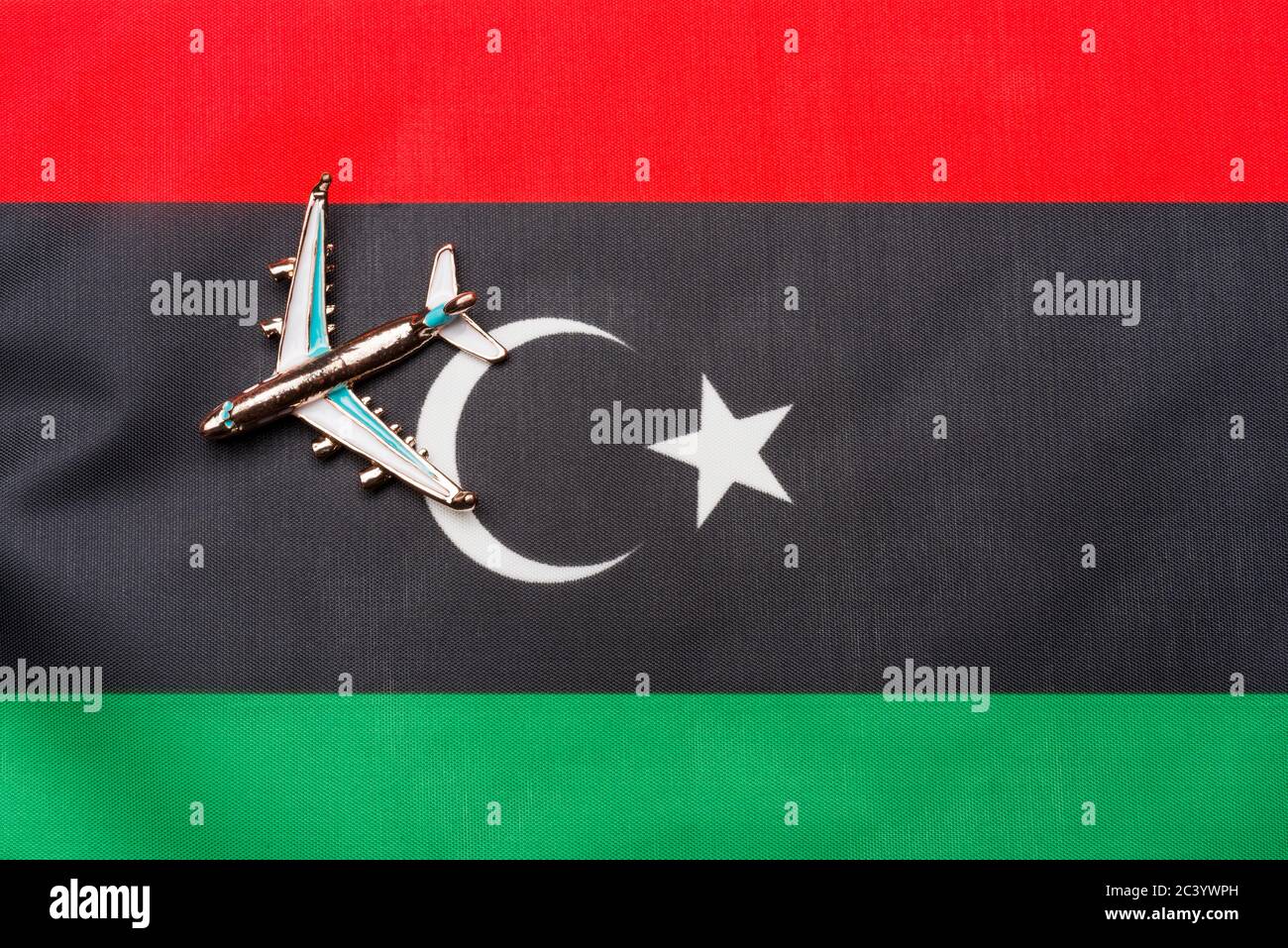 Plane over the flag of Libya island travel and tourism concept. Toy plane on a flag in the background. Stock Photo