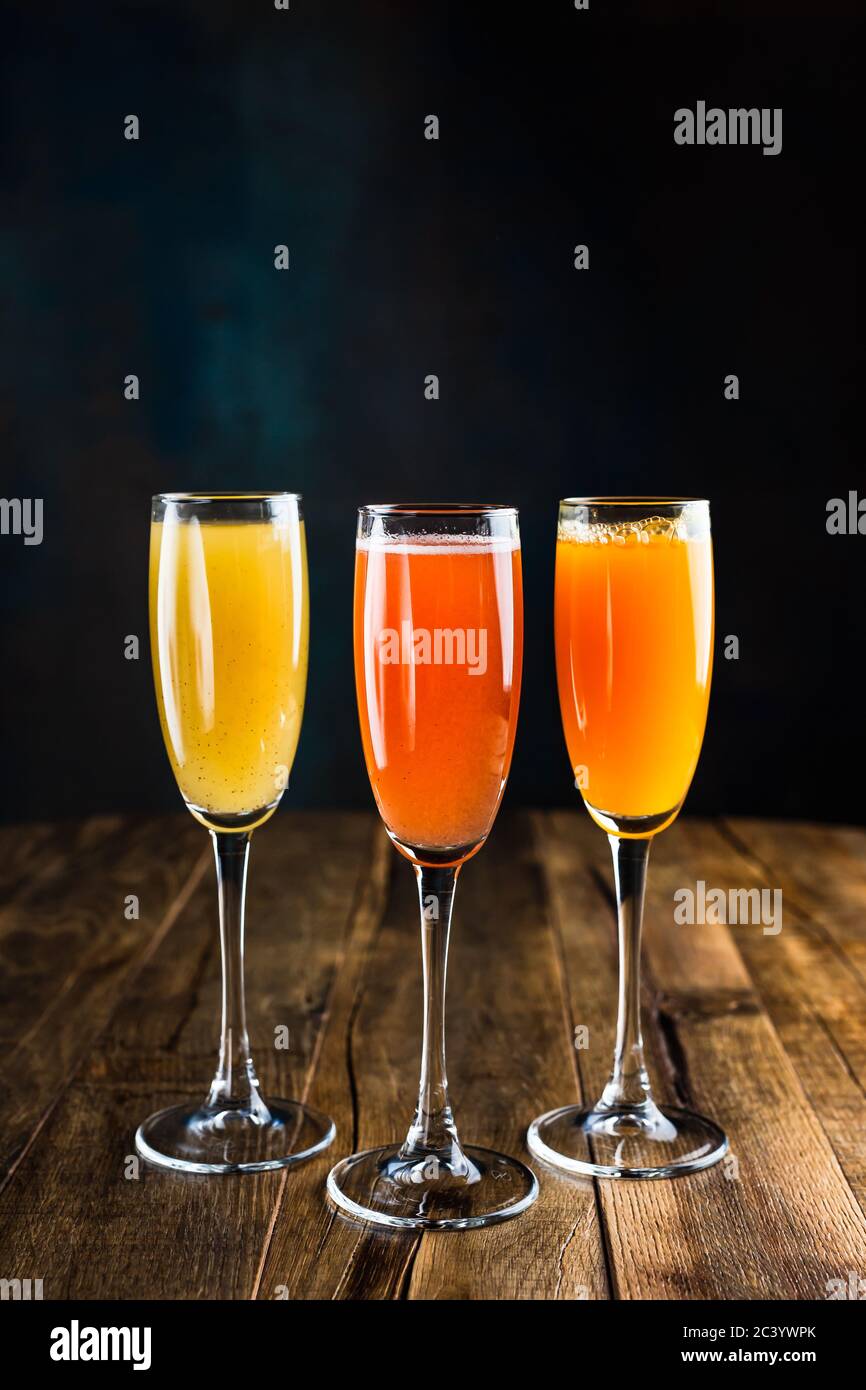 Three different sparkling fruity cocktails, red, yellow and orange, in flute glasses Stock Photo