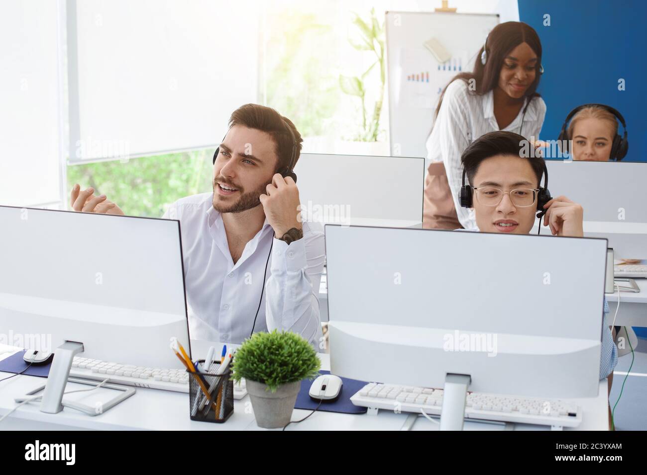 Group of helpline operators at work in modern call center office Stock
