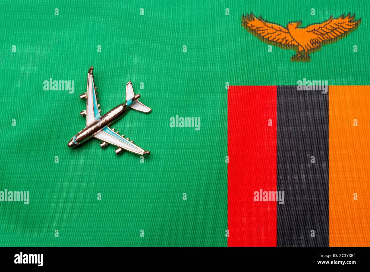 Airplane over Zambia flag travel concept. Toy plane on a flag in the background. Stock Photo