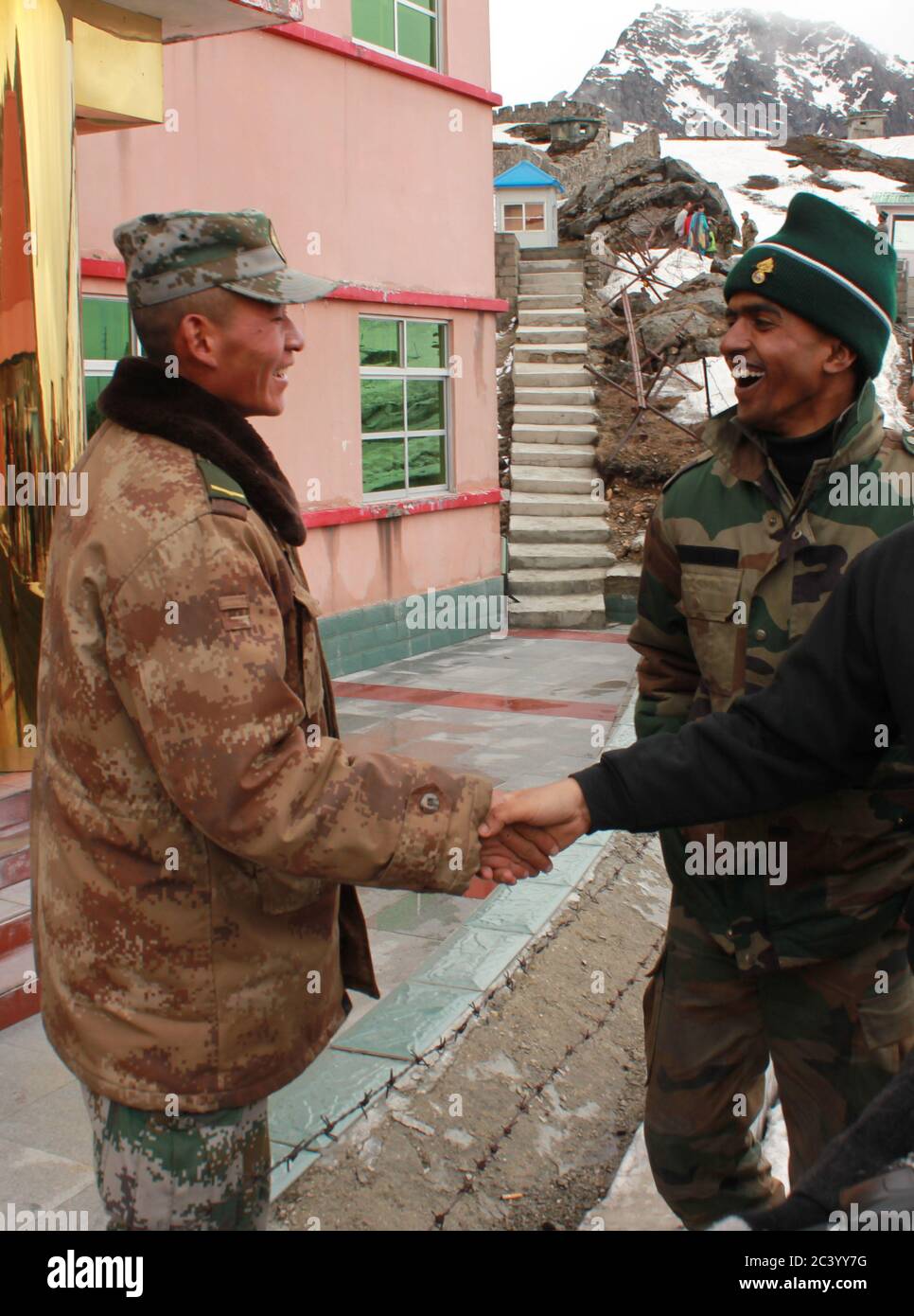 Chinese PLA soldier shakes hands with a tourist while sharing a laugh with an Indian Troop at Nathula Pass India-China Border Pass in Sikkim, India Stock Photo