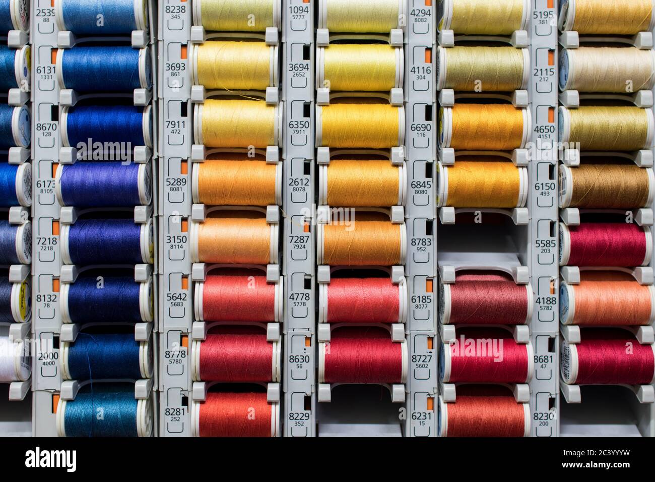 Colored spools of sewing thread exposed in a shelf dedicated to the ...