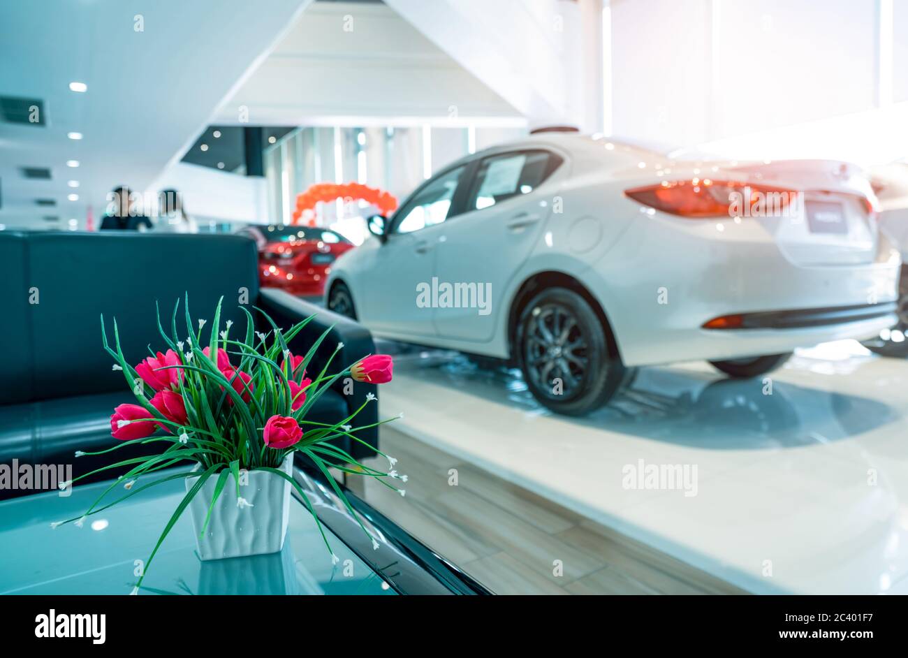 Fake red flowers in ceramic white vase on blurred background of sale