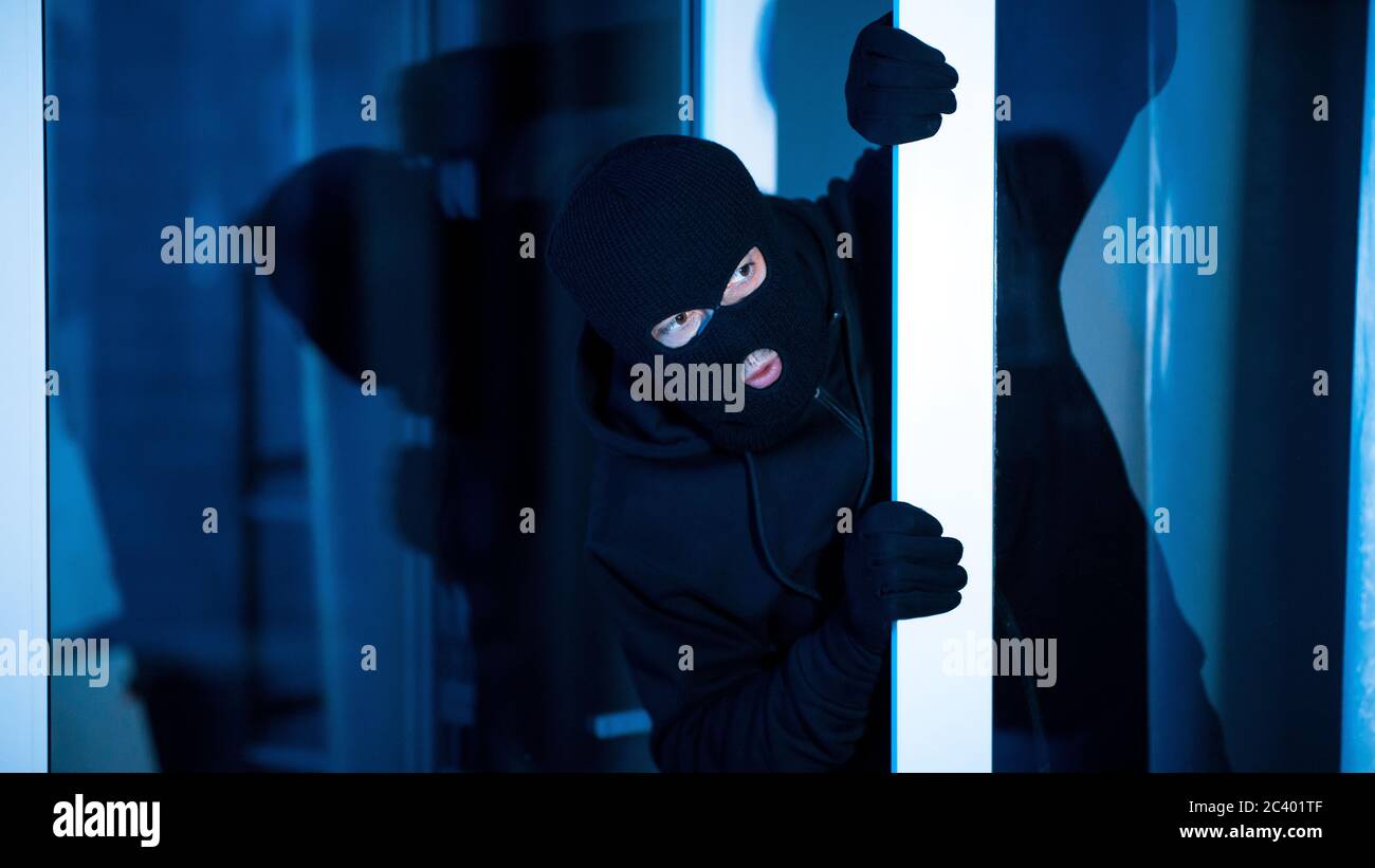 Intruder breaking into apartment or office looking inside Stock Photo