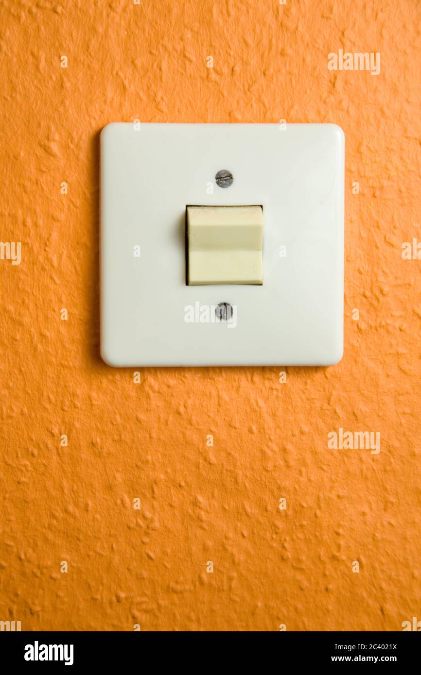 Square light switch on wall with orange wallpaper Stock Photo