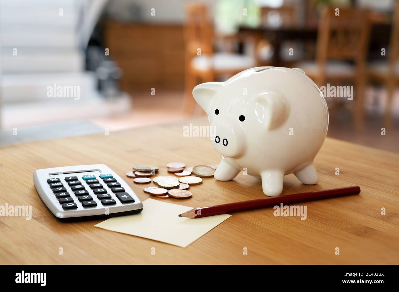 Economy concept, calculator with coins, pencil and a piggy bank on a table in the living room, calculating finances and saving household money, copy s Stock Photo
