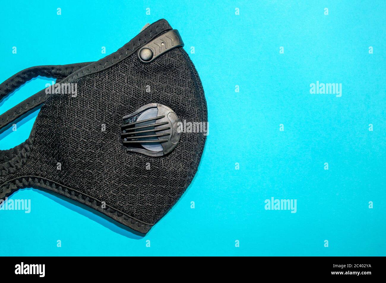 Black activated carbon dust mask with filters on blue background with