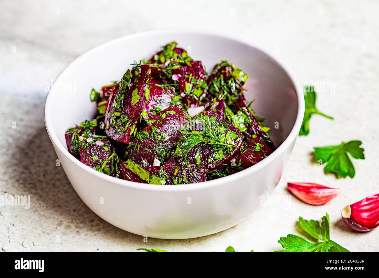 Beetroot salad with garlic and herbs in a gray bowl on a light background. Stock Photo