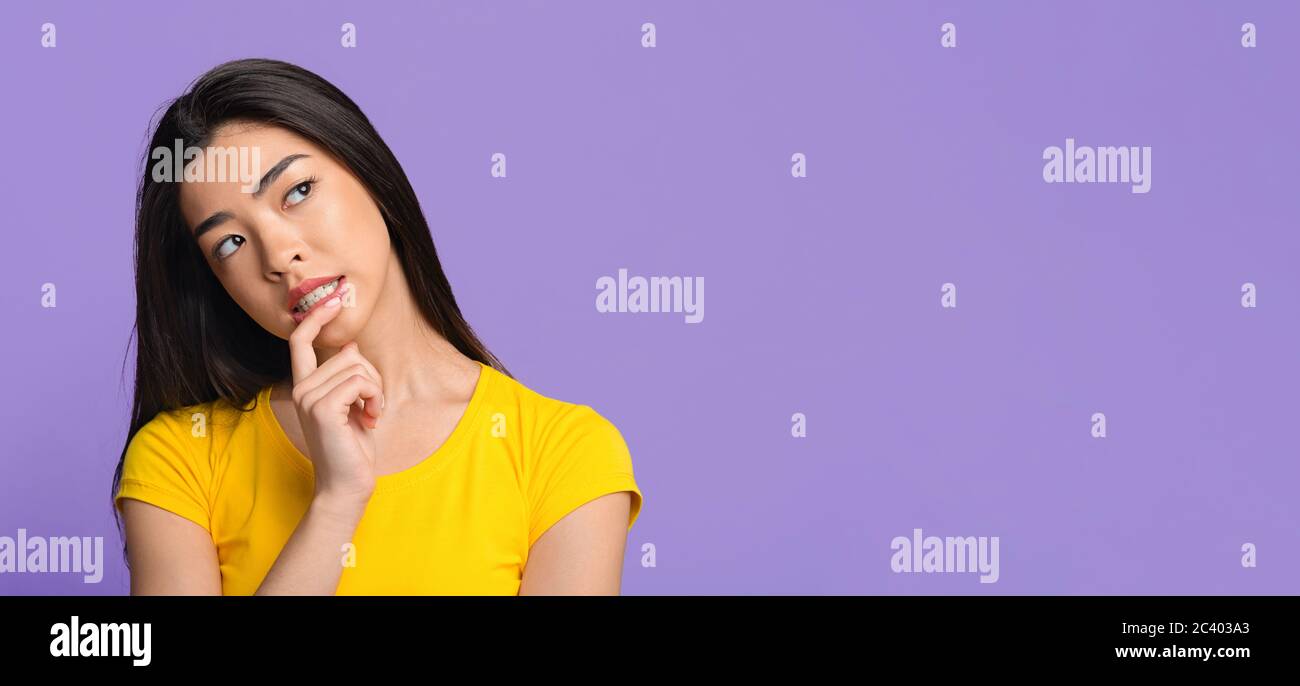 Interesting Offer. Pensive asian girl thinking about something, looking sceptically away Stock Photo