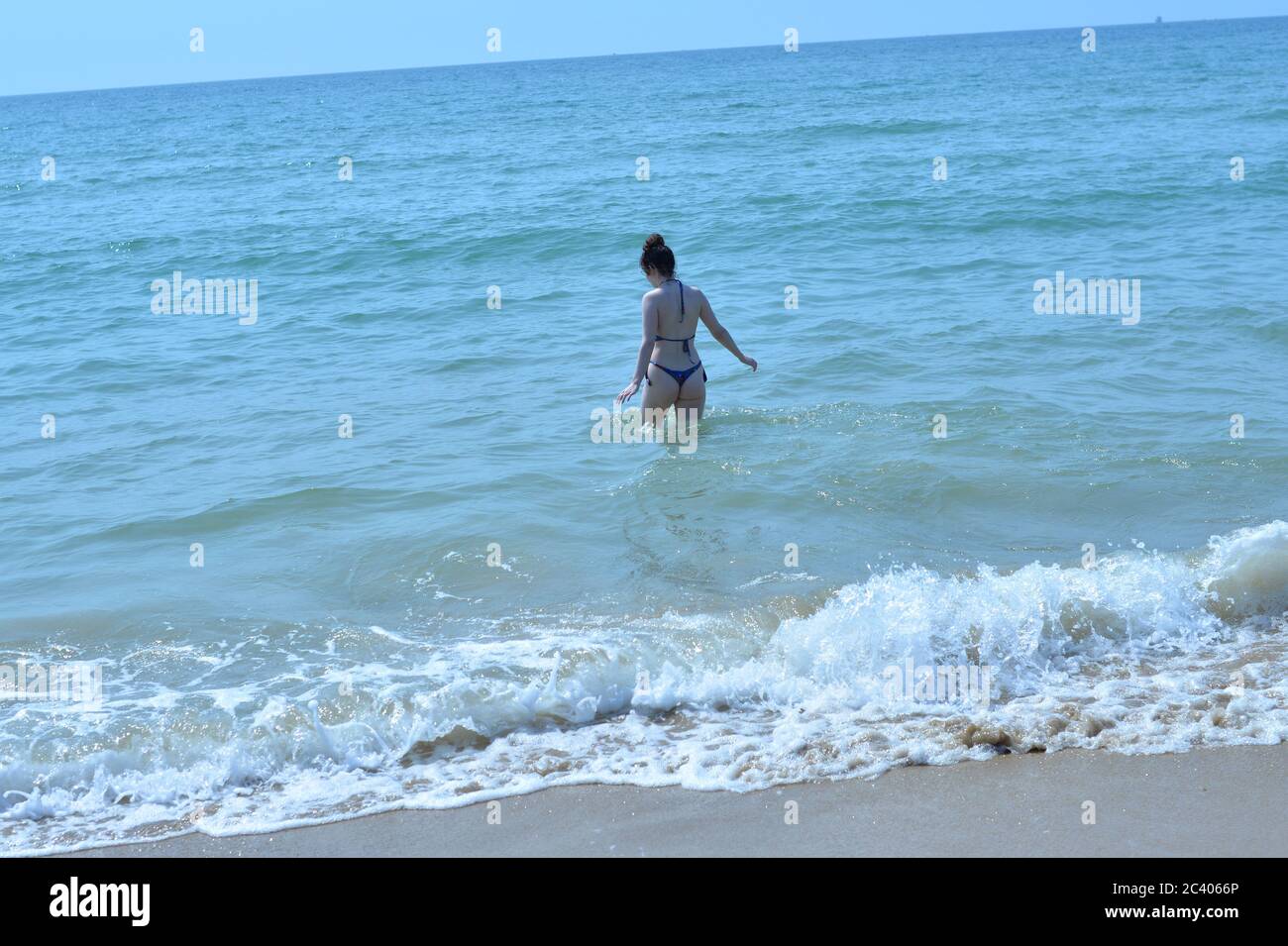 A young woman in a skimpy bikini ventures into the blue sea in the hot sunshine, Bournemouth, Dorset, UK, 23rd June 2020, Weather. A heatwave is building and temperatures are expected to reach 30 degrees. Stock Photo