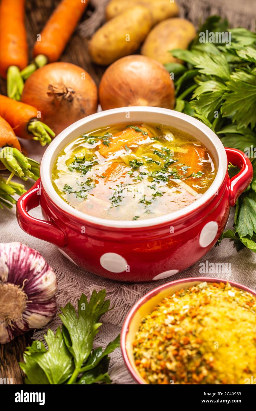 Chicken soup broth in a vintage bowl with homemade noodles carrot onion celery herbs garlic and fresh vegetables Stock Photo